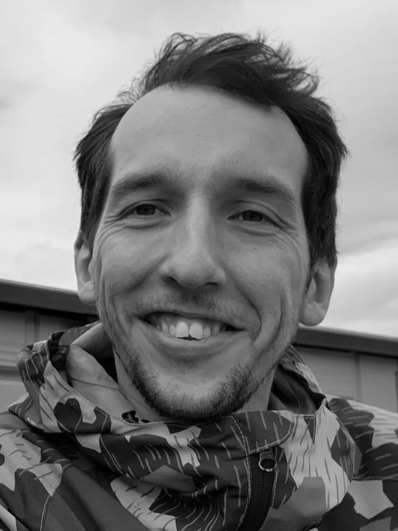 A black-and-white portrait of Connor Manson smiling.